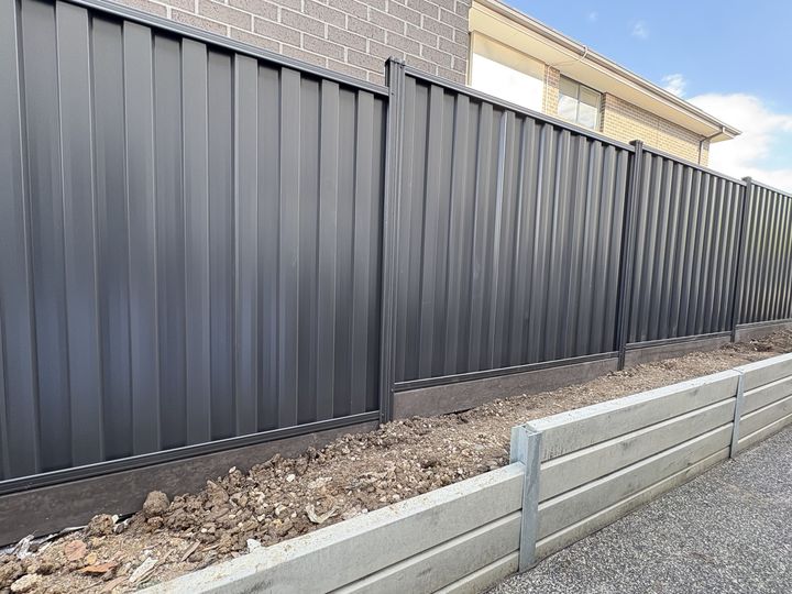 Dark Colorbond fence and retaining sleepers by HD Fencing